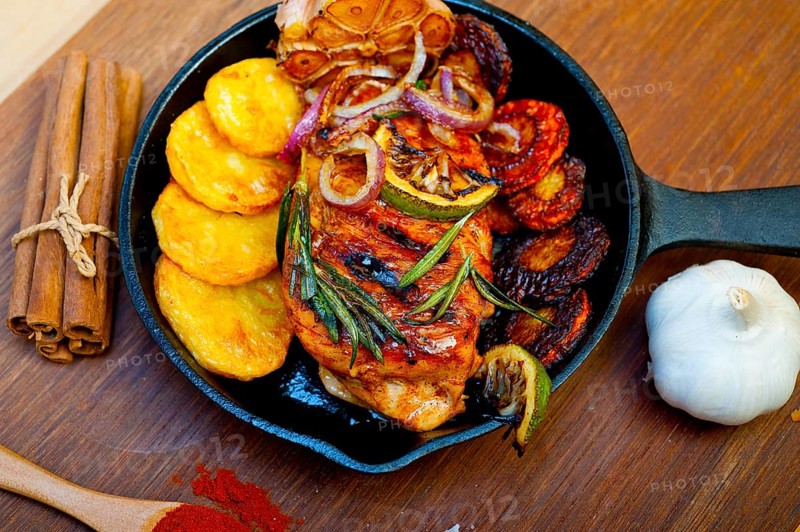 Roasted grilled BBQ chicken breast with herbs and spices rustic style on iron skillet