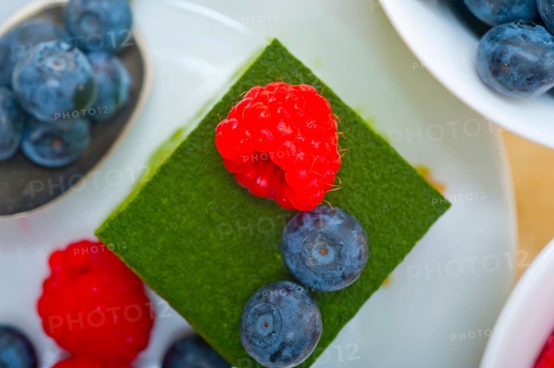 Green tea matcha mousse cake with raspberries and blueberries on top