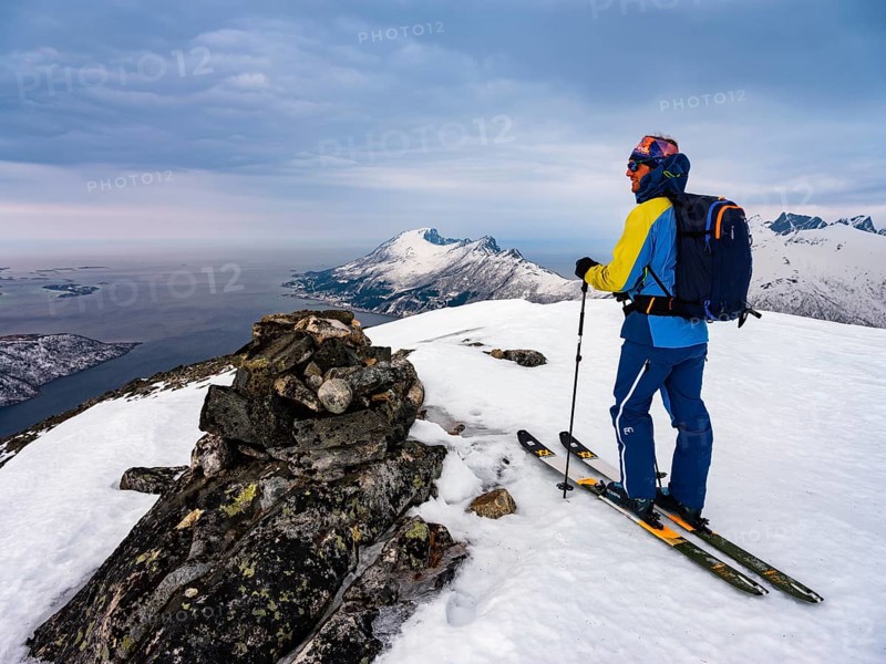 Ski mountaineers at the summit of Flobjoern with a view over the Bergsfjord