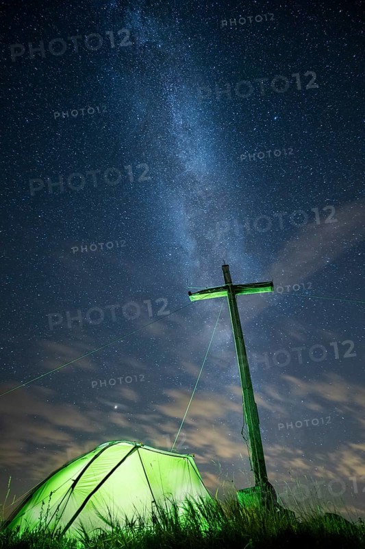 Green tent with summit cross under a starry sky on Portlakopf
