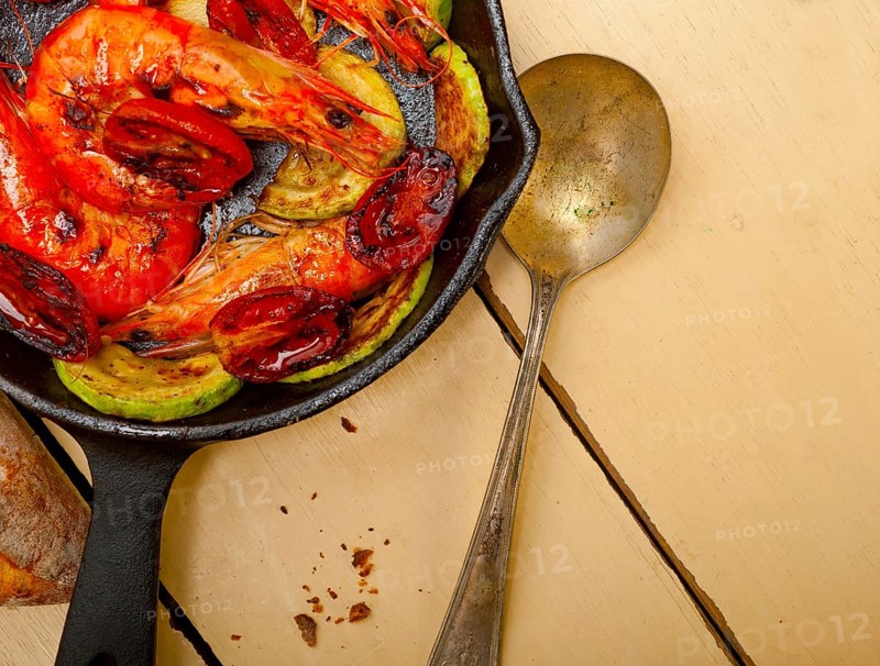 Roasted shrimps on cast iron skillet with zucchini and tomatoes