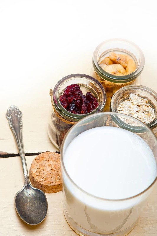 Healthy breakfast ingredients milk oat cashew nuts dried cramberry craisinns