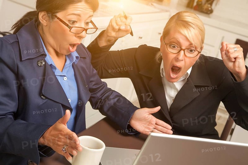 Businesswomen celebrate success on the laptop in the kitchen