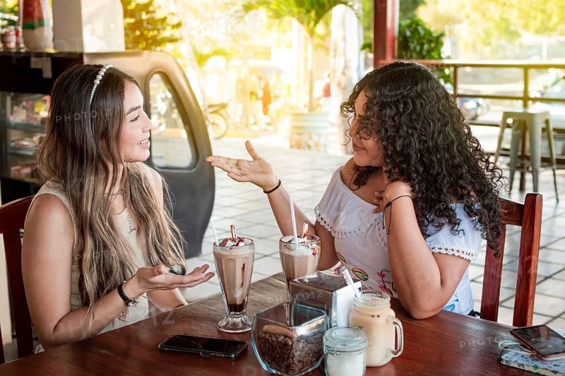 Two cute girls having a conversation in a coffee shop