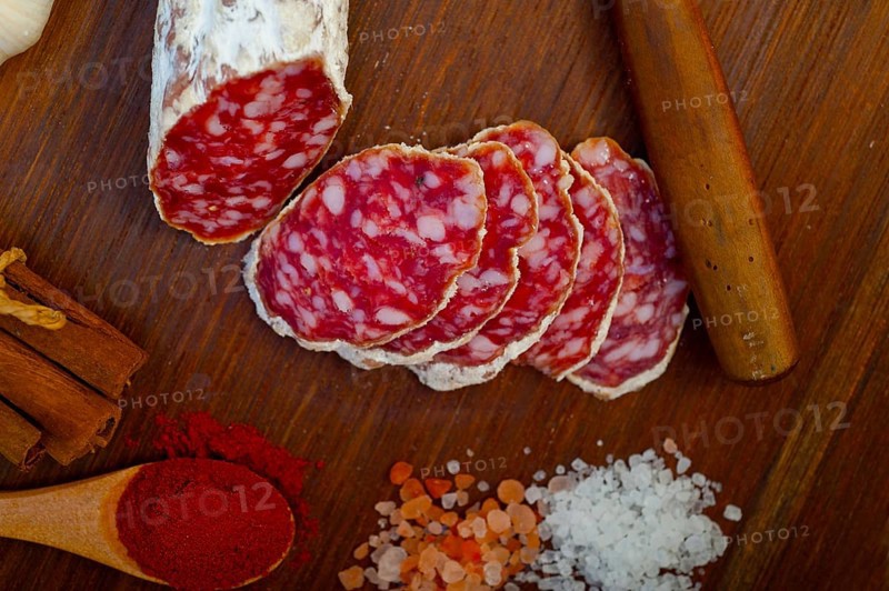 Traditional Italian salame cured sausage sliced on a wood board