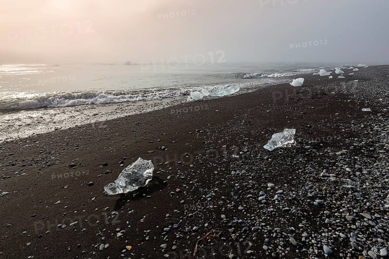 Ice crystals and pebbles on the black lava beach