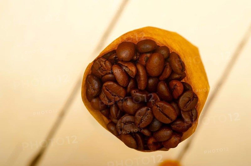 Espresso coffee beans on a paper cone cornucopia over white background