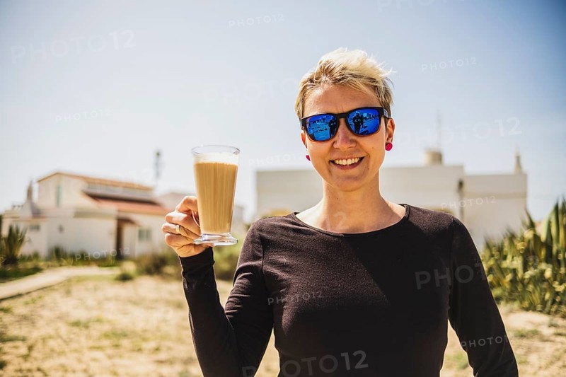 Happy woman with big coffee with milk during vacations in Portugal