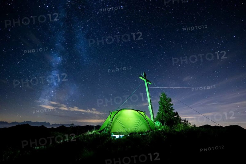 Green tent with summit cross under a starry sky on Portlakopf