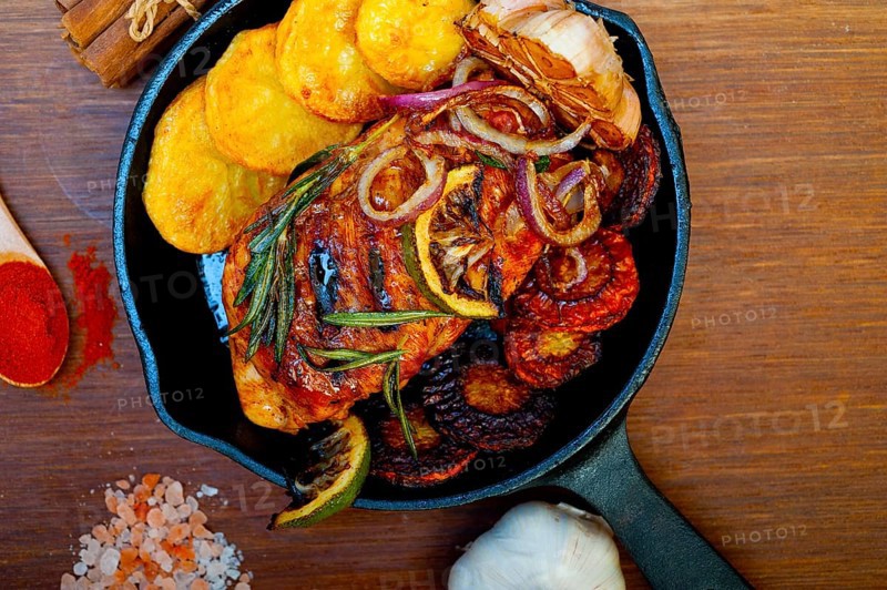 Roasted grilled BBQ chicken breast with herbs and spices rustic style on iron skillet