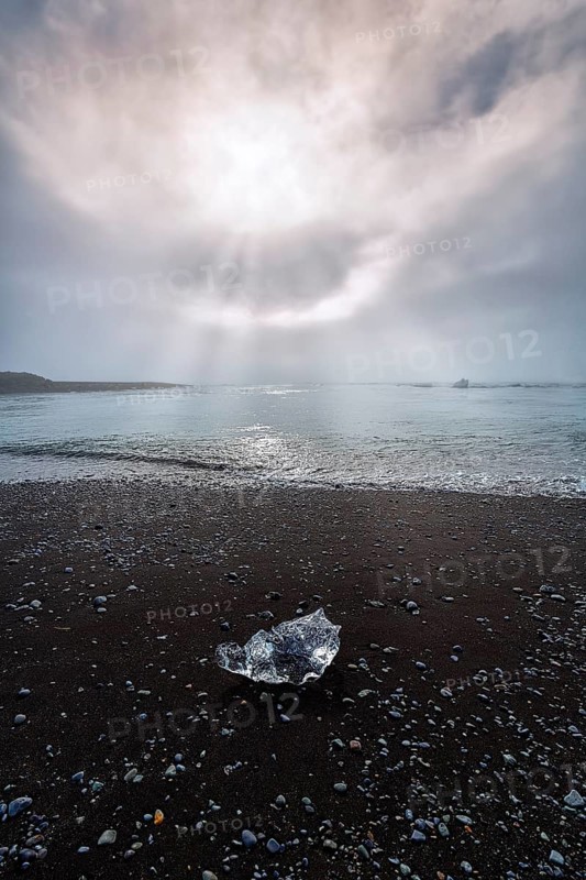 Ice crystal and pebbles on the black lava beach