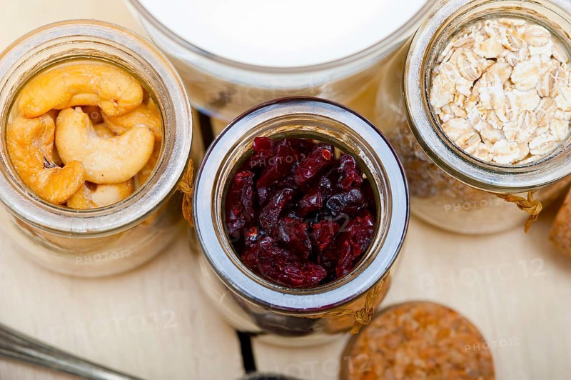 Healthy breakfast ingredients milk oat cashew nuts dried cramberry craisinns