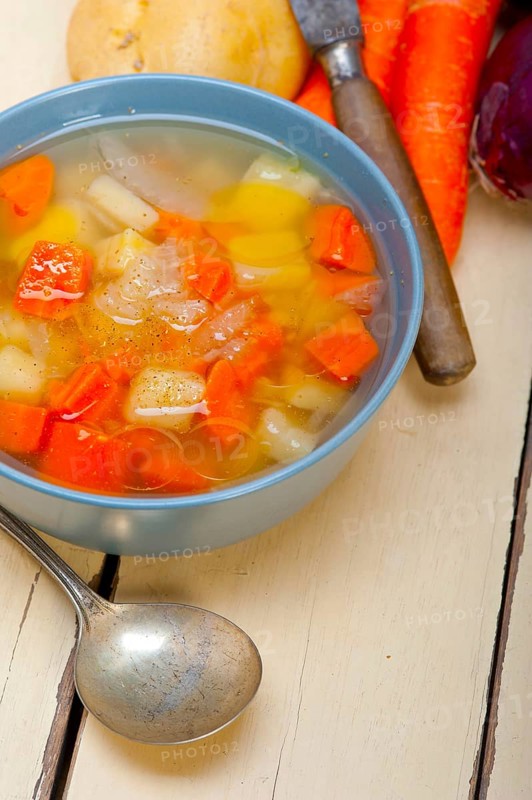 Traditional Italian minestrone soup on a rustic table with ingredients