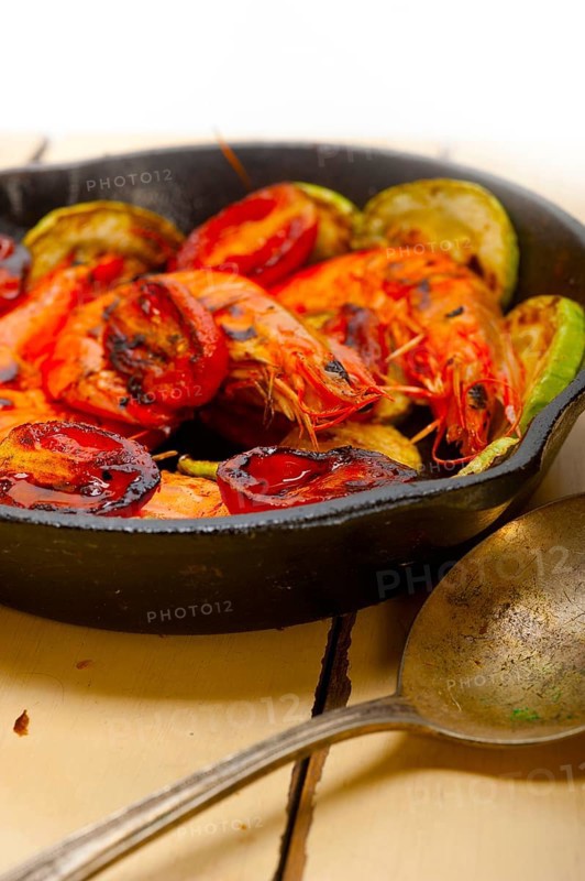 Roasted shrimps on cast iron skillet with zucchini and tomatoes