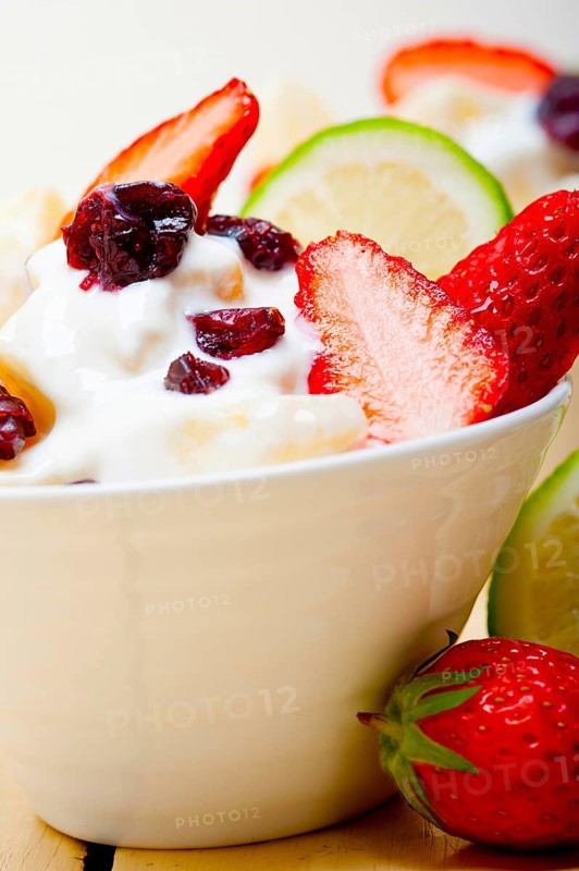 Fruit and yogurt salad healthy breakfast over white wood table