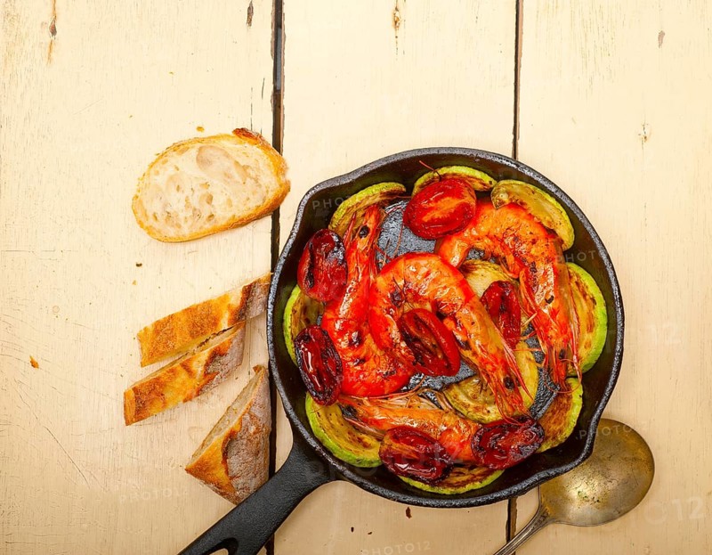 Roasted shrimps on cast iron skillet with zucchini and tomatoes
