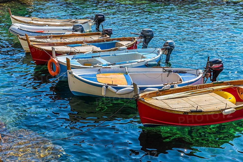 Colourful fishing boats reflected in the water in the harbour of Manarola