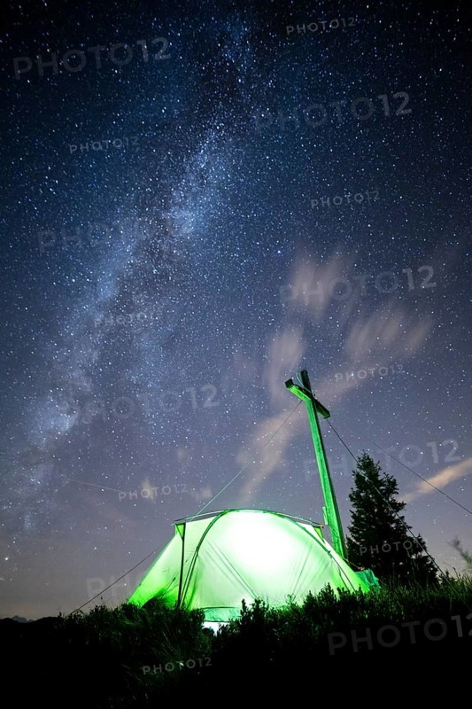 Green tent with summit cross under a starry sky on Portlakopf
