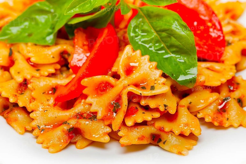 Italian pasta farfalle butterfly bow-tie with tomato basil sauce over white rustic wood table