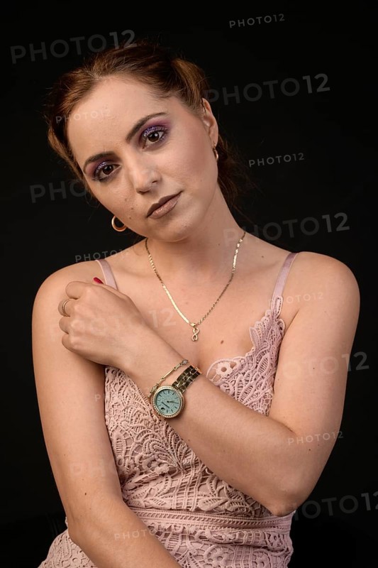 Pretty young woman with made-up eyes in sleeveless pink dress against black background