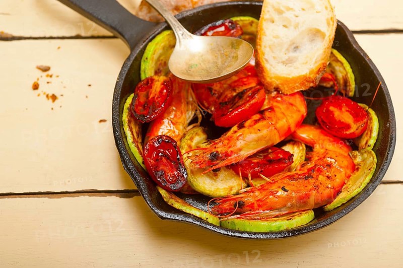 Roasted shrimps on cast iron skillet with zucchini and tomatoes