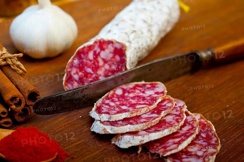 Traditional Italian salame cured sausage sliced on a wood board