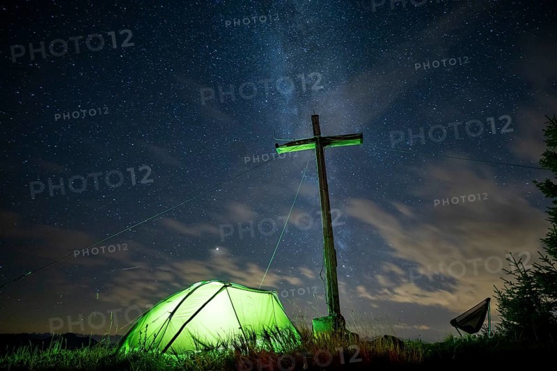 Green tent with summit cross under a starry sky on Portlakopf