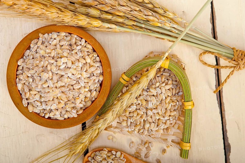 Organic wheat grains over rustic wood table macro closeup