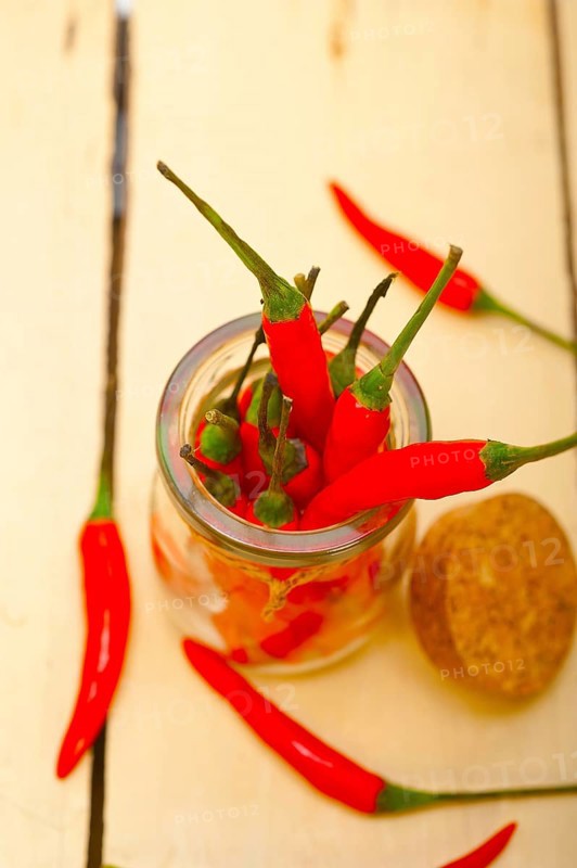 Red chili peppers on a glass jar over white wood rustic table