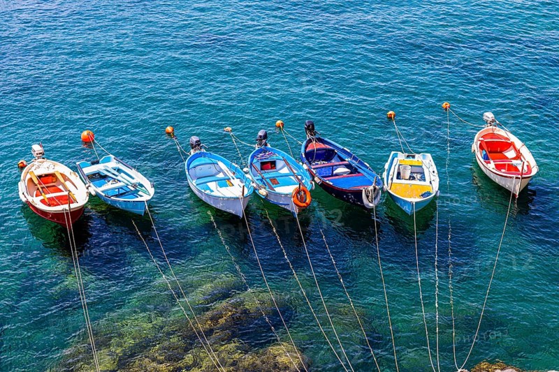 Colourful fishing boats attached to the rock lie in the turquoise water in the harbour of Riomaggiore