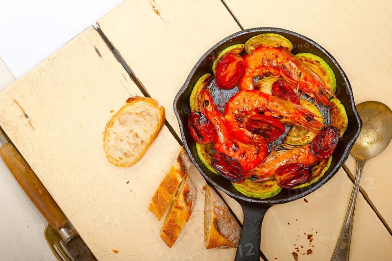 Roasted shrimps on cast iron skillet with zucchini and tomatoes