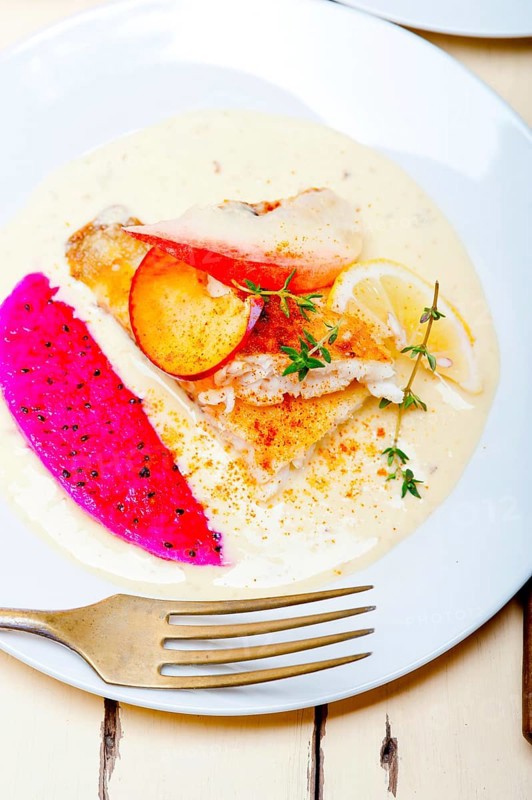 Sea bream orata fillet butter pan fried with fresh peach prune and dragonfruit slices thyme on top