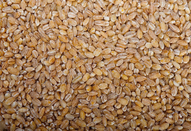 Organic wheat grains over rustic wood table macro closeup
