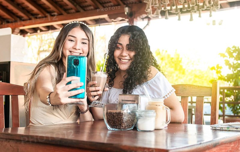 Two girls taking a selfie and drinking coffee