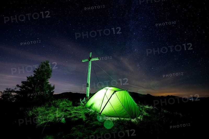 Green tent with summit cross under a starry sky on Portlakopf