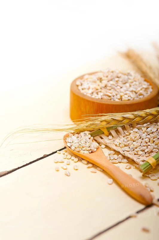 Organic barley grains over rustic wood table macro closeup