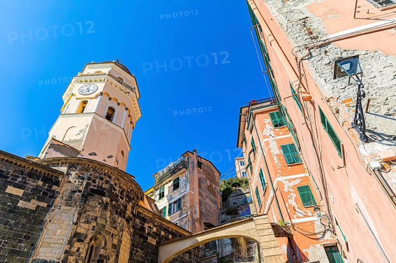 The steeple of the church of Santa Margherita di Antiochia and nested houses built into the hillside with pastel-coloured facades