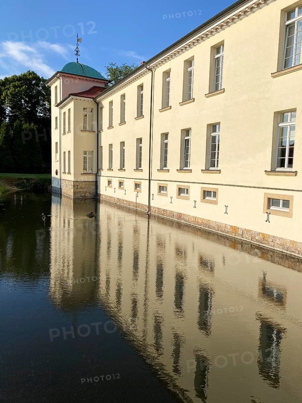View of classicist castle Westerholt with reflection of building in historical moat