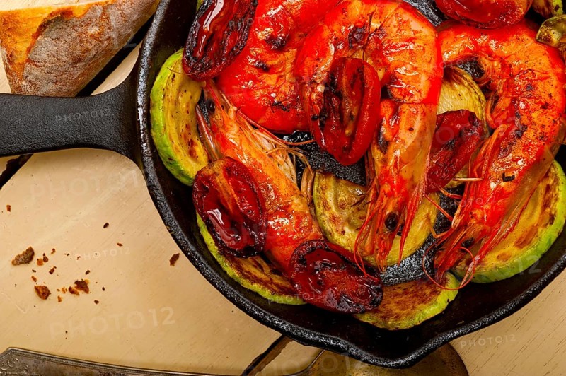 Roasted shrimps on cast iron skillet with zucchini and tomatoes