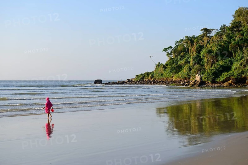 Little girl with sand bucket on lonely beach