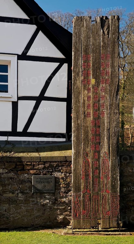Wooden stele made of ship planks in front of half-timbered house at St. Pancratius Church on the occasion of the 1000th anniversary of the parish