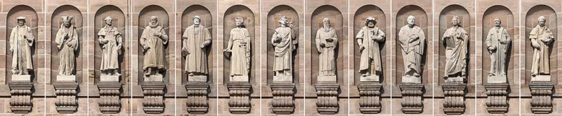 Collage of thirteen stone sculptures of historical legal scholars on the main facade of the Justice Building