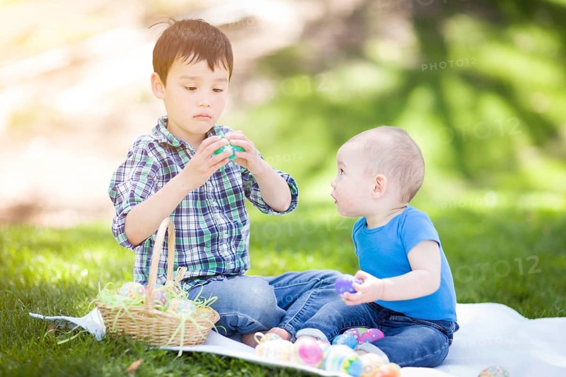 mixed-race chinese and caucasian boys outside in park playing with easter eggs