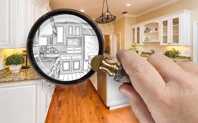 Hand holding magnifying glass revealing custom kitchen design drawing and photo combination