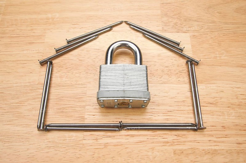 House of nails with lock on a wood background