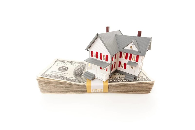 Small house on stack of hundred dollar bills isolated on a white background
