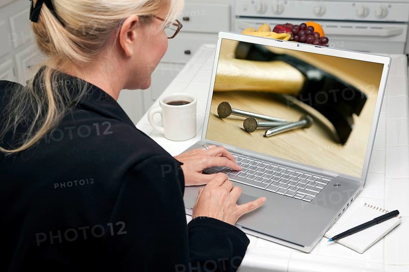 Woman in kitchen using laptop to research home improvement. screen can be easily used for your own message or picture. picture on screen is my copyright as well