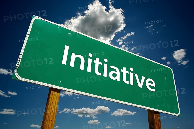 Initiative green road sign over dramatic blue sky and clouds with clipping path