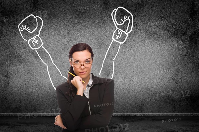 Young adult woman with pencil in front of boxing gloves on hands drawing on wall with copy sapce