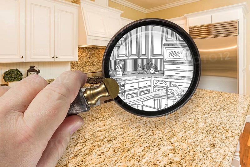 Hand holding magnifying glass revealing custom kitchen design drawing and photo combination